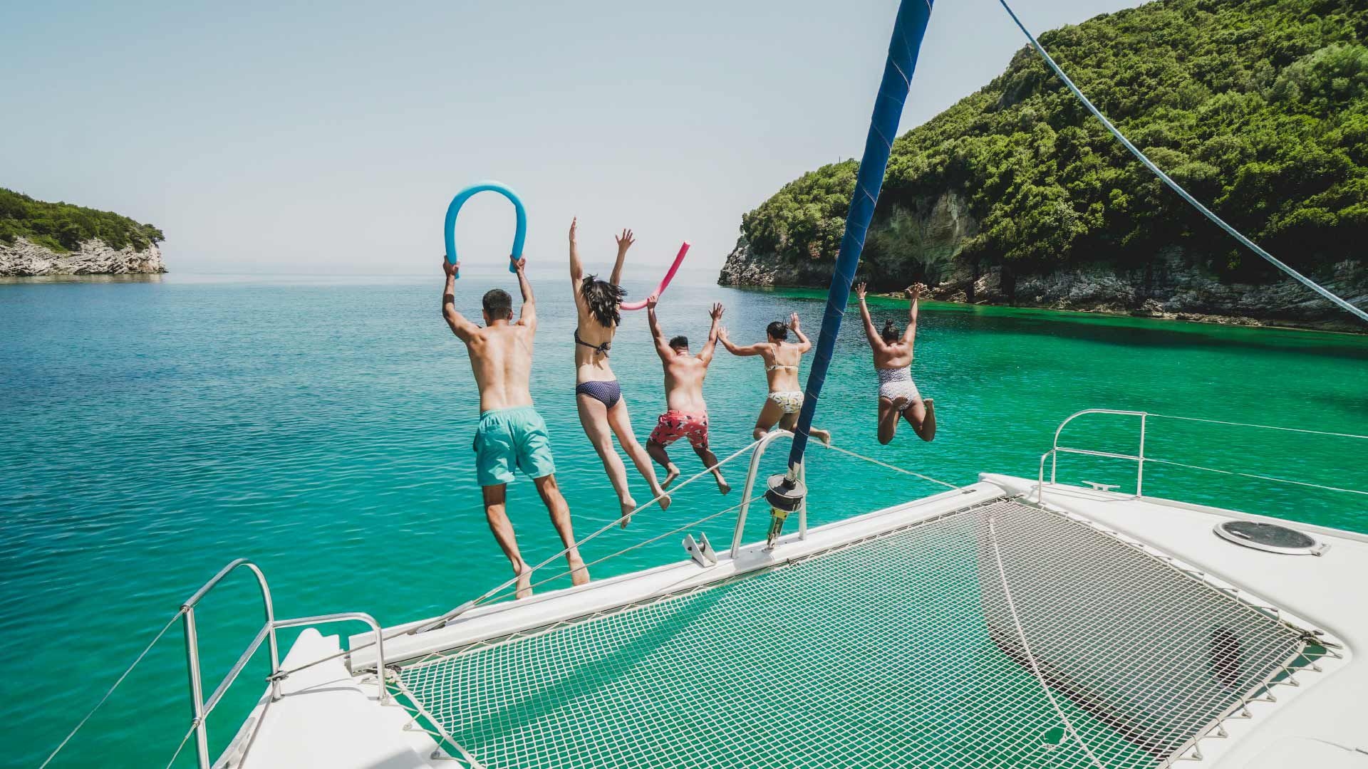 Group of people jump into the water from a MedSailors catamaran