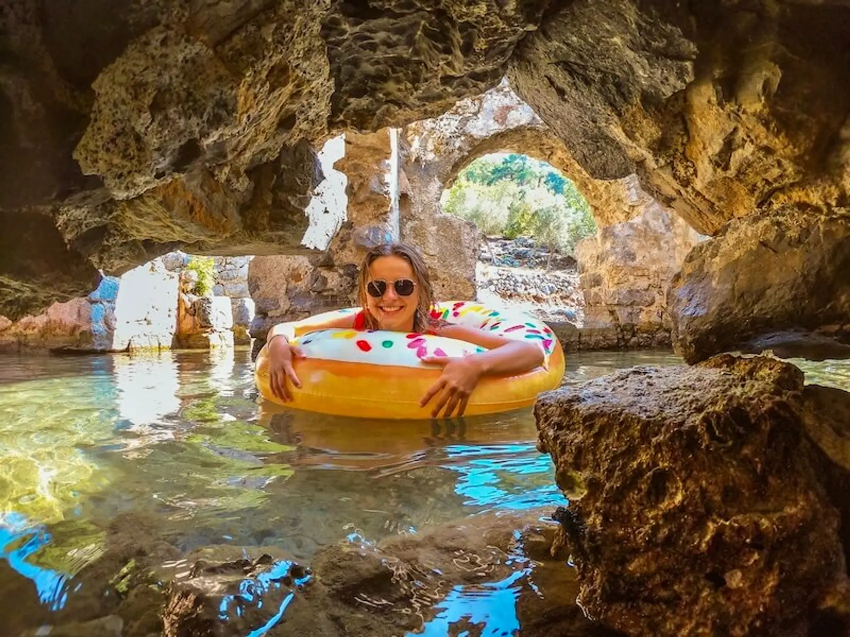 A girl in a floatie swimming in ruins of Cleopatra's bathhouse in Turkey.