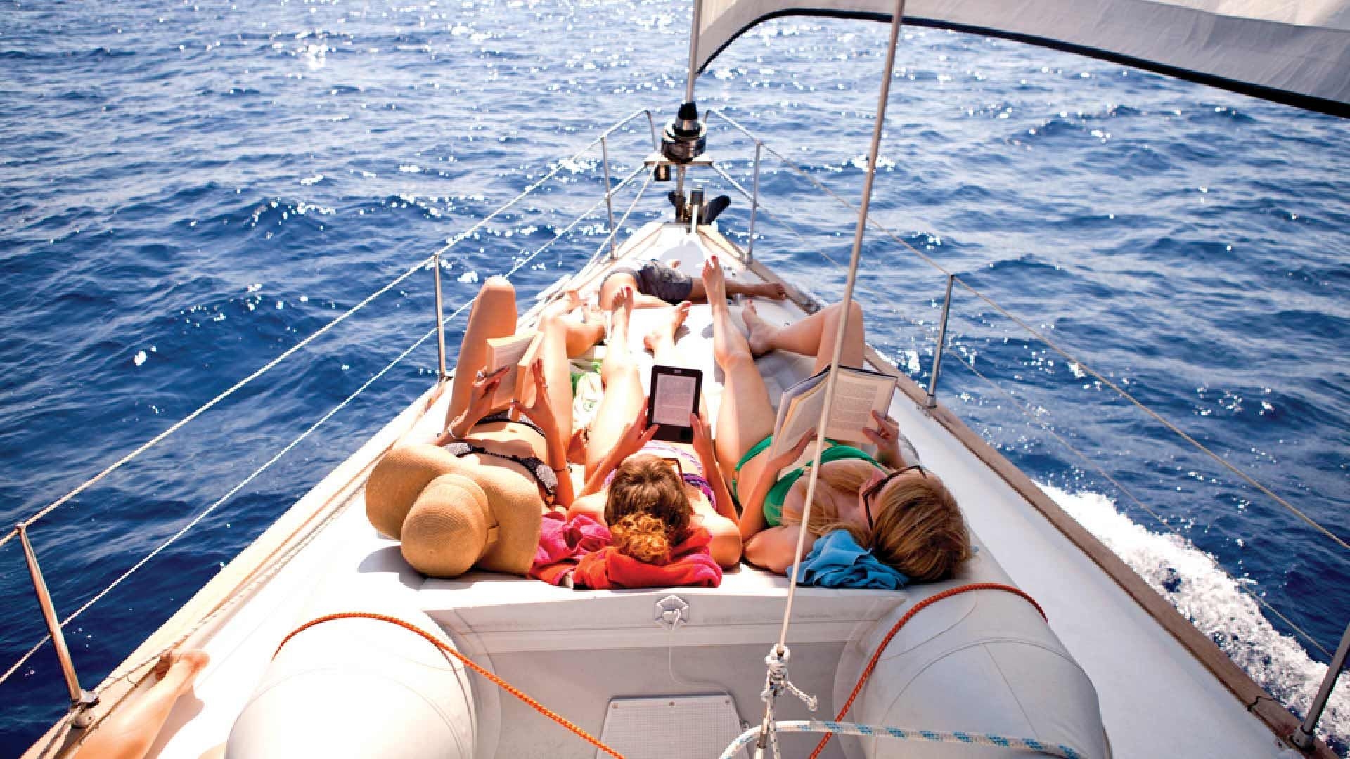 People on the bow of a yacht reading.